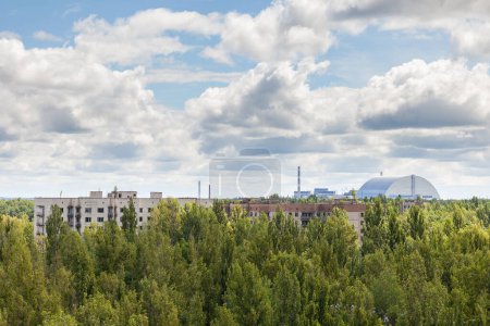 Photo for Abandoned city of Pripyat against the backdrop of the Chernobyl nuclear power plant covered with a new sarcophagus - Royalty Free Image
