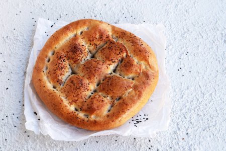 Téléchargez les photos : Pain de ramadan turc traditionnel avec papier cuisson sur fond texturé blanc, vue ci-dessus - en image libre de droit