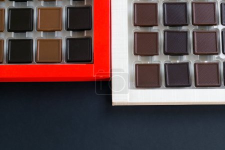Téléchargez les photos : Chocolat Madlen en forme de carré laiteux et amer, conçu en boîte sur une surface noire.La fête du sucre ou toute célébration du festival. - en image libre de droit