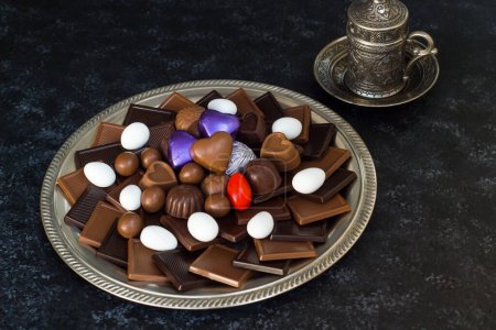 Téléchargez les photos : Chocolat Madlen de forme carrée, laiteuse et amère, conçu en plateau rutique sur surface noire.La fête du sucre ou toute célébration de festival. - en image libre de droit
