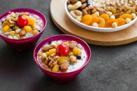Téléchargez les photos : Asure traditionnelle de dessert turc, ou pudding de Noé dans des bols en verre de couleur rose élégant sur une surface sombre - en image libre de droit