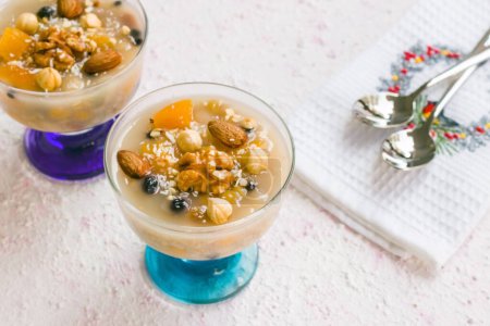 Téléchargez les photos : Asure traditionnelle de dessert turc, pudding de Noé dans des bols en verre élégants sur une surface texturée avec des cuillères en métal - en image libre de droit