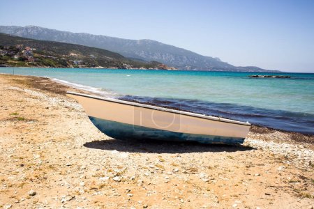 Téléchargez les photos : Un bateau en bois sur la plage tranquille sans personne, au bord de la mer - en image libre de droit