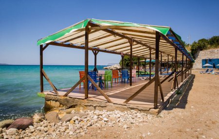 Téléchargez les photos : Cafétéria de plage avec tables colorées, chaises longues et auvents abrités sur la mer - en image libre de droit