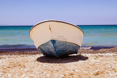 Téléchargez les photos : Un bateau en bois sur la plage tranquille sans personne, au bord de la mer - en image libre de droit