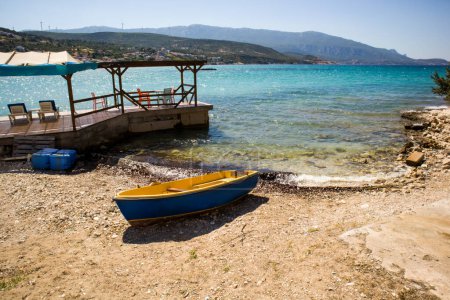 Téléchargez les photos : Un bateau en bois sur la plage tranquille sans personne et une jetée en bois sur la mer - en image libre de droit