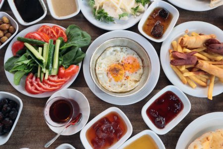 Téléchargez les photos : Petit déjeuner traditionnel turc avec poêle à œufs, fruits frais, confiture, pommes de terre frites sur table en bois. - en image libre de droit