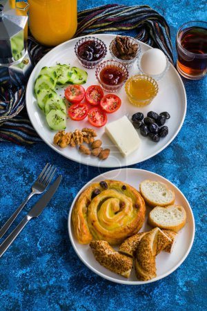 Téléchargez les photos : Assiette de petit déjeuner blanche avec tomates cerises tranchées, concombre et oeuf bouilli avec tasse à thé sur la surface bleue - en image libre de droit