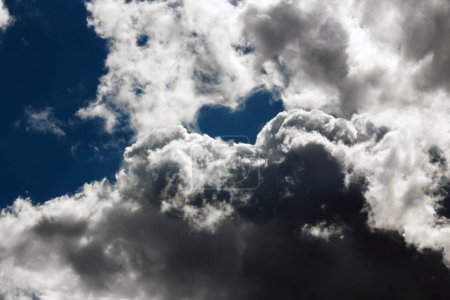 Téléchargez les photos : Un ciel orageux dramatique avec des nuages blancs, sombres et gris et un ciel bleu profond en forme de cœur - en image libre de droit