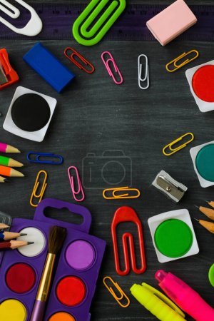 Téléchargez les photos : L'école colorée fournit ensemble aquarelle, crayons et crayons sur fond noir poussiéreux de craie. - en image libre de droit