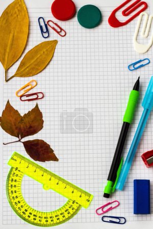 Téléchargez les photos : Fournitures scolaires colorées avec feuilles d'automne et espace de copie sur un carnet à carreaux - en image libre de droit