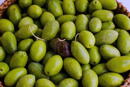 Téléchargez les photos : Olives vertes fraîchement récoltées dans un panier en osier sur surface blanche, vue de dessus - en image libre de droit