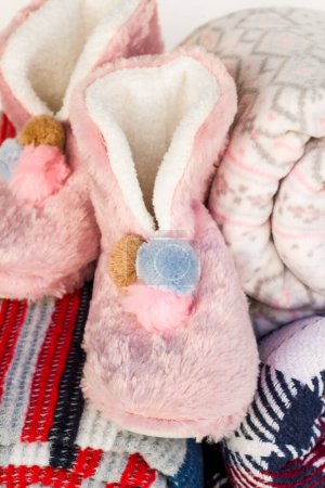 Téléchargez les photos : Des bottes douces et roses en peluche d'hiver ont été conçues sur une surface blanche avec des couvertures roulées. - en image libre de droit