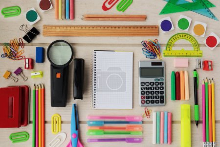 Téléchargez les photos : Fournitures scolaires colorées conçues sur une table en bois, avec carnet à carreaux vierges, Image conceptuelle de l'éducation - en image libre de droit