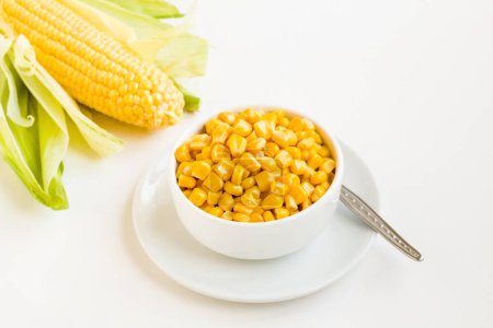 Téléchargez les photos : Maïs doux frais bouilli dans un bol avec épi de maïs naturel sur surface blanche - en image libre de droit