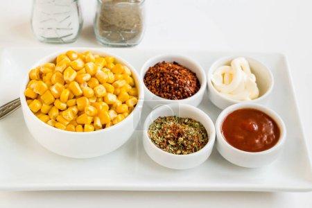 Téléchargez les photos : Grains de maïs naturels fraîchement bouillis avec diverses épices sur une assiette blanche - en image libre de droit