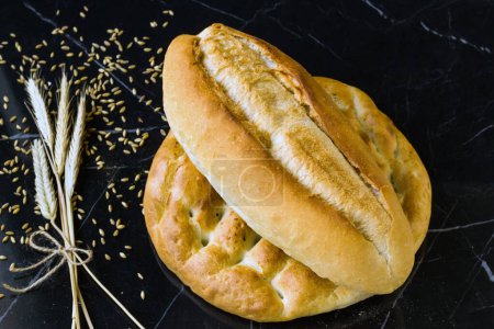 Téléchargez les photos : Pain Ramadan turc traditionnel avec un pain standard et des épis de blé sur une surface noire - en image libre de droit