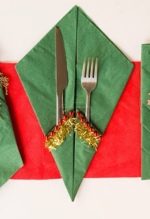 Téléchargez les photos : Serviettes de Noël de couleur rouge et verte pliées en différentes formes sur une surface blanche avec ensemble de couverts. - en image libre de droit