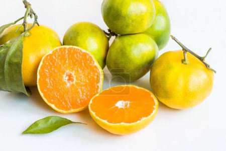Téléchargez les photos : Les mandarines vertes et jaunes, dont l'une a été coupée en deux, ont été conçues sur un fond blanc. - en image libre de droit