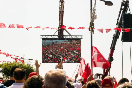 Téléchargez les photos : Célébrant avec des drapeaux turcs et un écran géant, des personnes non identifiées ont le dos tourné et les mains en l'air. - en image libre de droit