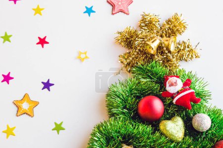 Téléchargez les photos : Le sapin de Noël décoré avec des accessoires du Nouvel An a été conçu avec une surface blanche demi-regardant avec des étoiles colorées. - en image libre de droit