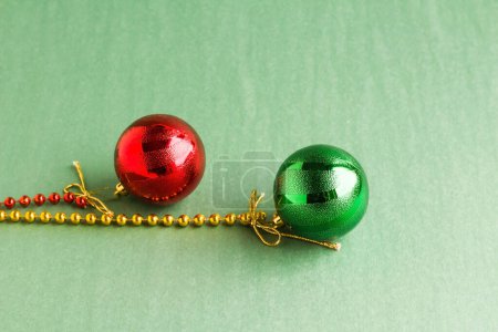 Téléchargez les photos : Chaîne de couleurs jaune et rouge attachée, boules rouges et vertes du Nouvel An sur surface verte avec espace de copie - en image libre de droit