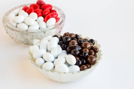 Téléchargez les photos : Bonbons aux amandes de couleur blanche et rouge et boules de chocolat noir conçues moitié et demie dans le bol à bonbons rond - en image libre de droit
