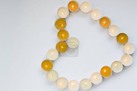 Téléchargez les photos : Brûler de petites bougies chauffe-plat en forme de cœur sur une surface blanche, image conceptuelle - en image libre de droit