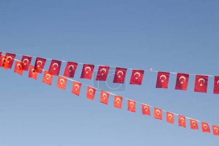 Small Turkish Flags hung in two rows on the blue sky for the national celebration