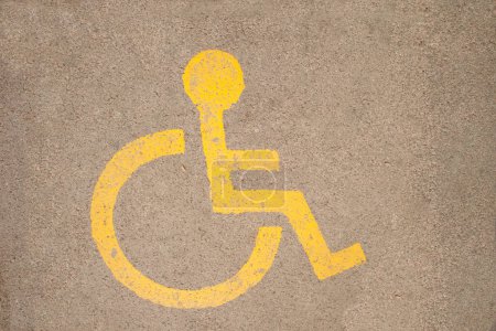 Téléchargez les photos : Chaise handicapée symbole dessiné sur l'asphalte avec de la peinture jaune - en image libre de droit
