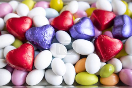 Téléchargez les photos : Des bonbons aux amandes colorées ont été conçus avec des chocolats enveloppés en forme de cœur. - en image libre de droit