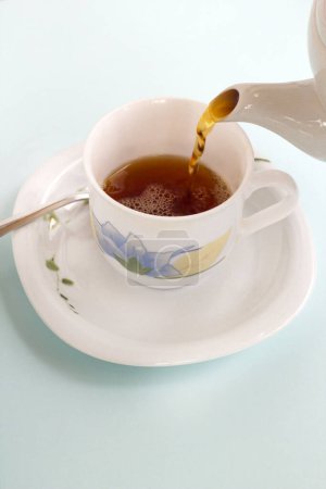 Téléchargez les photos : Le thé est versé de la théière en céramique dans la tasse, image verticale - en image libre de droit