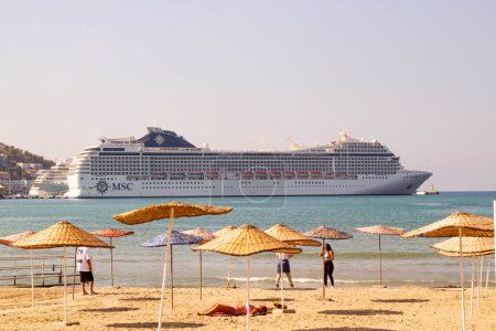 Téléchargez les photos : Kusadasi-Aydin-Turquie 10.17.2023 Deux bateaux de croisière attachés dans le port avec plage de sable fin et parasols - en image libre de droit