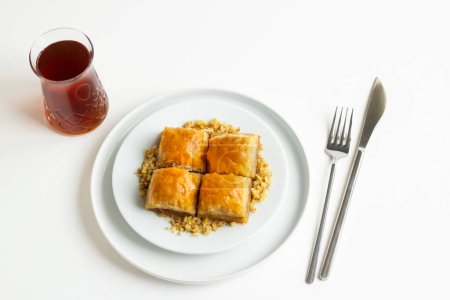 Traditional Turkish Pastry Dessert is Walnut Baklava in the white plate with walnuts,tea and copy space.