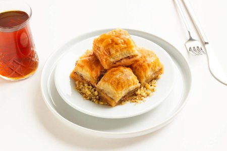 Traditional Turkish Pastry Dessert is Walnut Baklava in the white plate with walnuts,tea and copy space.