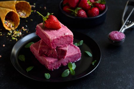 Téléchargez les photos : Glace aux fraises, conçue sur une assiette ronde noire, aux fraises fraîches - en image libre de droit
