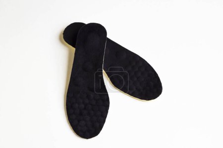 A pair of black colored,orthopedic men's shoe insoles on white surface with copy space