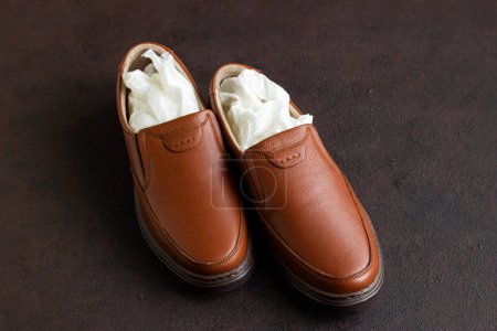 Téléchargez les photos : Une paire de chaussures neuves, inutilisées, en cuir pour homme dans un moule en papier sur une surface sombre - en image libre de droit