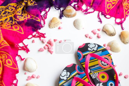 Téléchargez les photos : Pink women's beach shawl designed with mussel shells,flip flops and decorative stones on a white surface - en image libre de droit