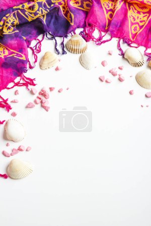 Téléchargez les photos : Pink women's beach shawl designed with mussel shells and decorative stones on a white surface - en image libre de droit