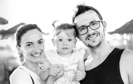 Téléchargez les photos : Photo de famille de souriant jeune maman et papa posant à la plage avec petite fille mignonne - Fête d'été - en image libre de droit
