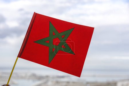 Hände mit marokkanischen Fahnen mit defokussiertem Hintergrund jubeln ihrer Fußballmannschaft bei der WM zu.