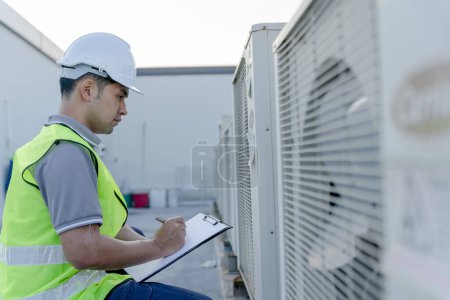 Photo for Asian maintenance engineer recheck works on the roof of factory. contractor  inspect compressor system and plans installation of air condition systems in construction site of modern buildings. - Royalty Free Image