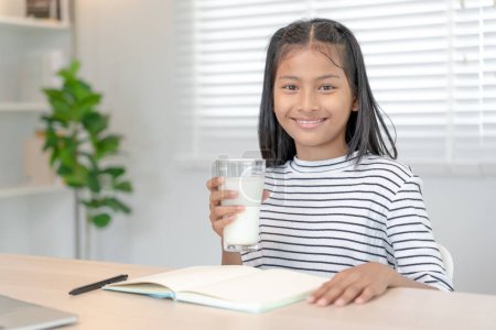 Photo for Children women drink milk to nourish the body and nourish the brain. asian young little girl learn at home. girl happy drink milk and read a book for exam, Homeschool. education, vitamins, development - Royalty Free Image