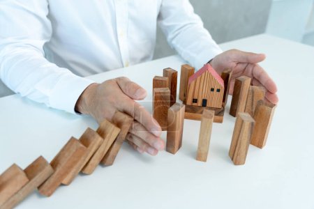 Téléchargez les photos : Insurance with hands protect domino. Businessman hands stop dominoes falling in house crisis. business risk control and planning and strategies to run prevent insurance businesses. - en image libre de droit