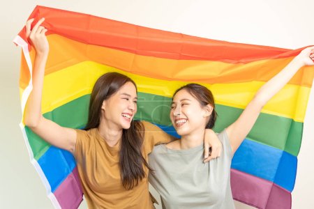 Foto de Grupo LGBT. Las parejas lesbianas guapas sonríen brillantemente cubren las banderas del arco iris. Asiática joven pareja abrazándose felizmente, amante en el amor, bisexualidades, homosexualidad, libertad, expresión, vida feliz - Imagen libre de derechos