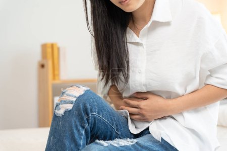 Photo for Stomach ache. Asian women have abdominal pain, indigestion, gastritis, menstrual cramps, flatulence, diarrhea, distention, colon cancer, belly inflammation problem, suffer food poisoning, abdomen - Royalty Free Image