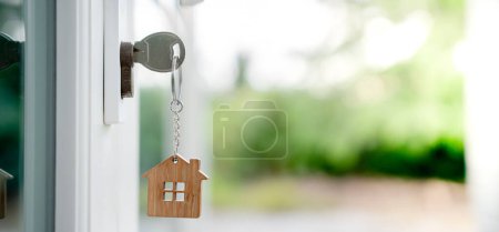 Hauseigentümerschlüssel zum Entriegeln des Hauses steckt in der Tür. Gebrauchtes Haus zu vermieten und zu verkaufen. Schlüsselanhänger weht im Wind. Hypothek für neues Eigenheim, kaufen, verkaufen, renovieren, investieren, Eigentümer, Nachlass