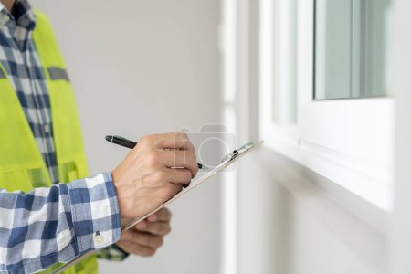 Téléchargez les photos : Inspector or engineer is inspecting construction and quality assurance new house using a checklist. Engineers or architects or contactor work to build the house before handing it over to the homeowner - en image libre de droit