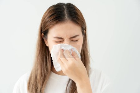 Photo for Pollen Allergies, asian young woman sneezing in a handkerchief or blowing in a wipe, allergic to wild spring flowers or blossoms during spring. allergic reaction, respiratory system problems - Royalty Free Image